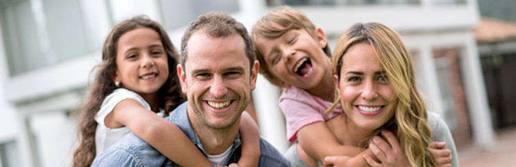 Mom and dad with young boy and young girl hanging on their backs